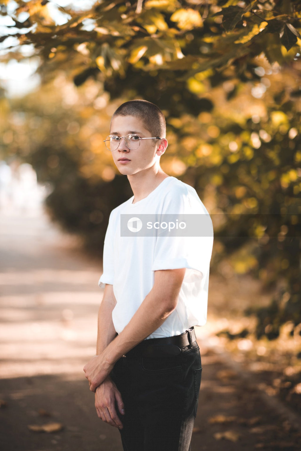 Man in white crew neck t-shirt and black pants standing on brown dirt road