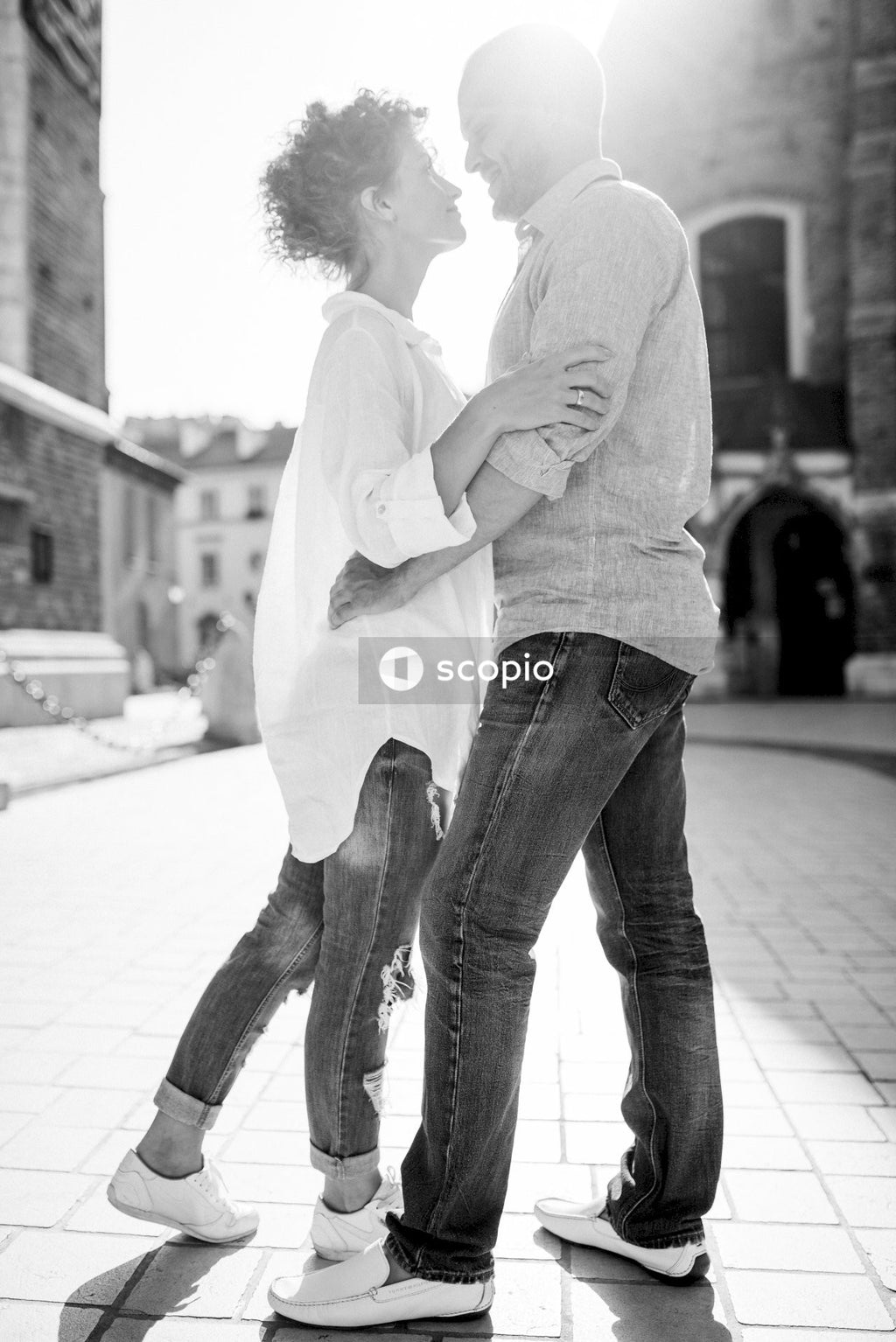 Man in white dress shirt and blue denim jeans hugging woman in white long sleeve shirt