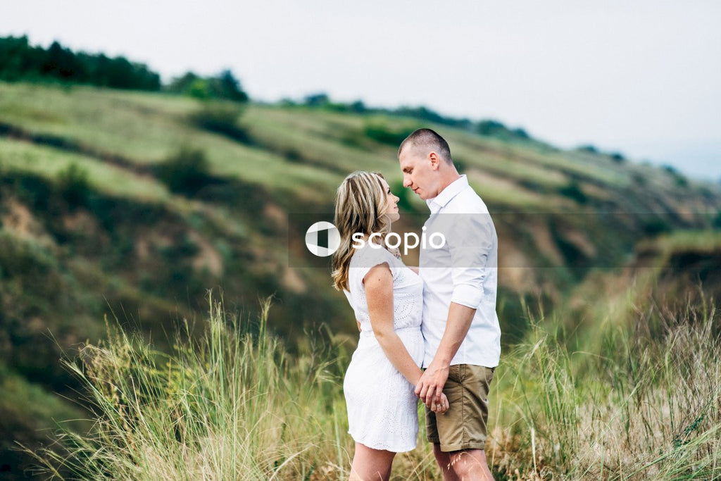 Man in white dress shirt and brown pants hugging woman in white long sleeve shirt