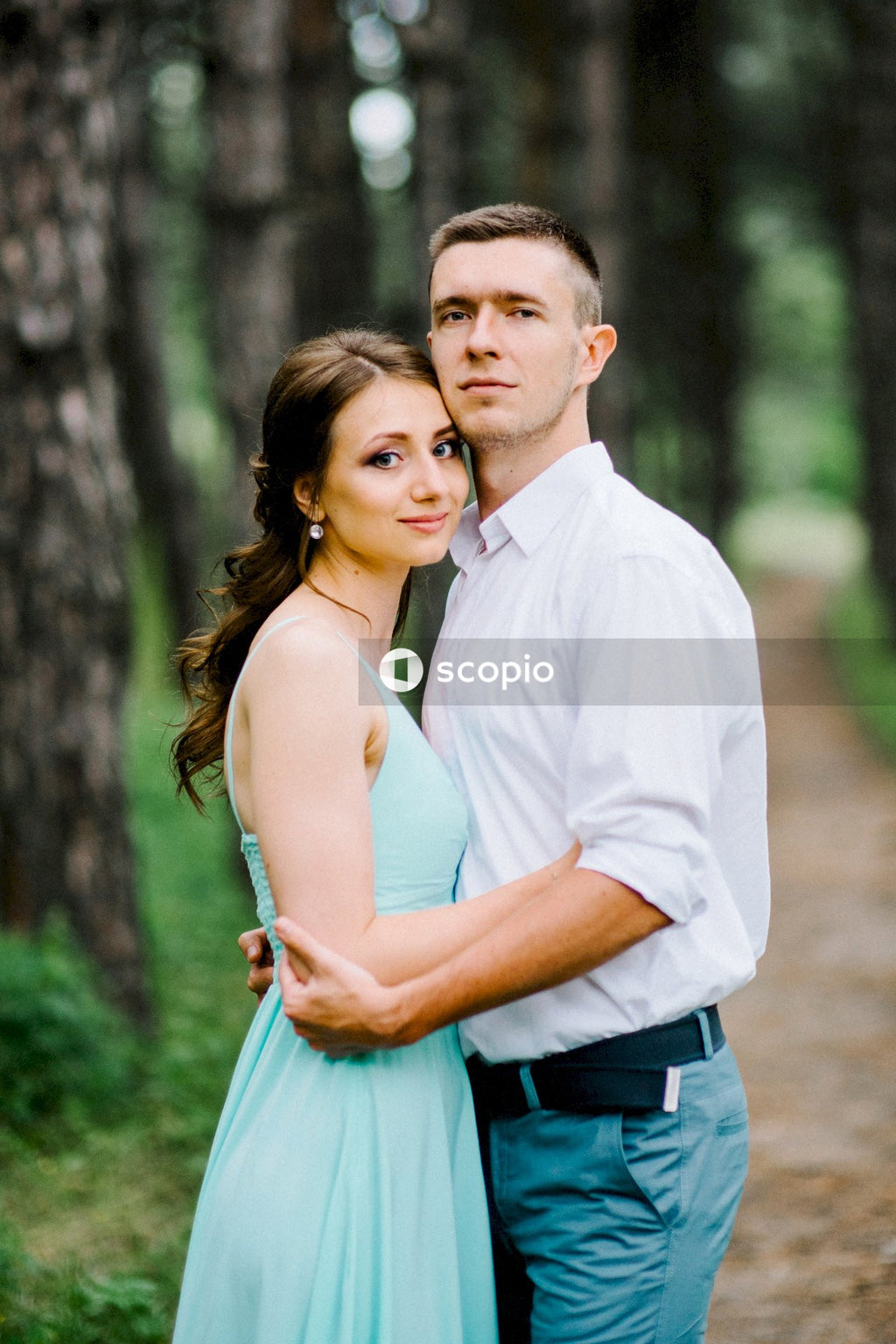 Man in white dress shirt hugging woman in blue dress