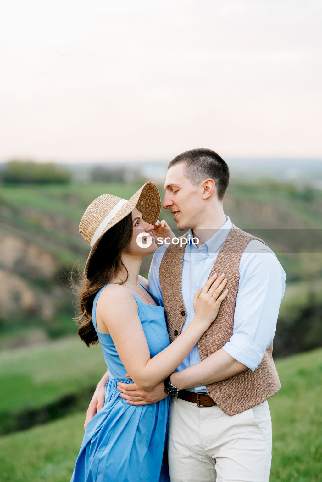 Man in white dress shirt hugging woman in blue sleeveless dress