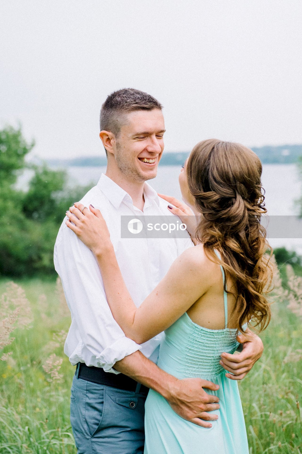 Man in white dress shirt hugging woman in teal spaghetti strap top