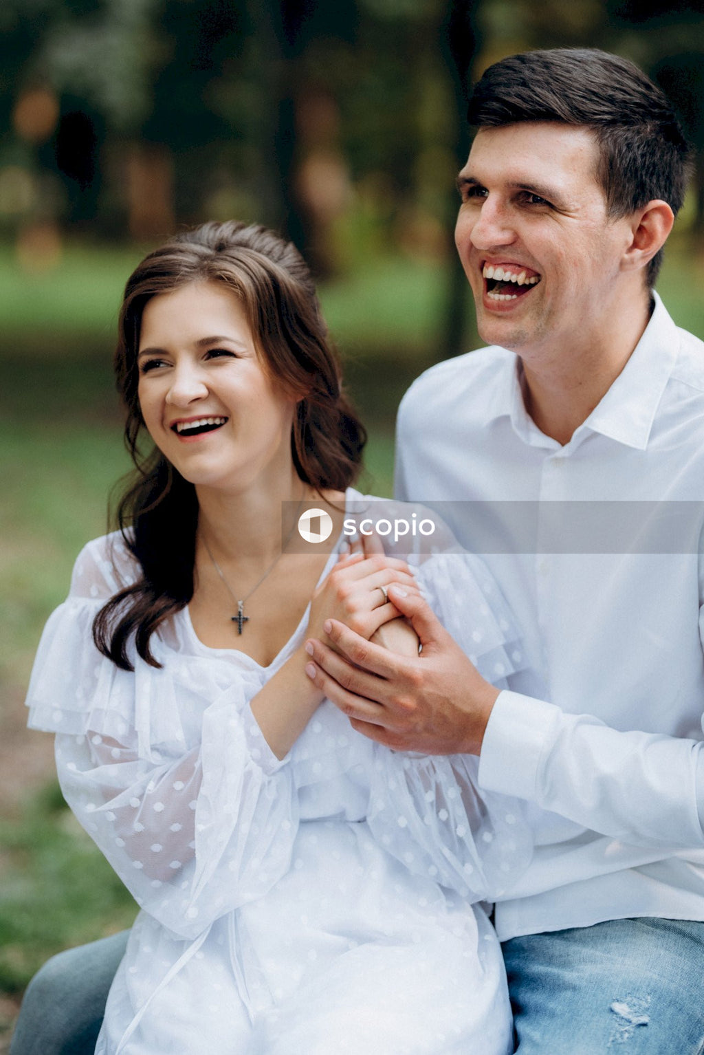 Man in white dress shirt hugging woman in white dress