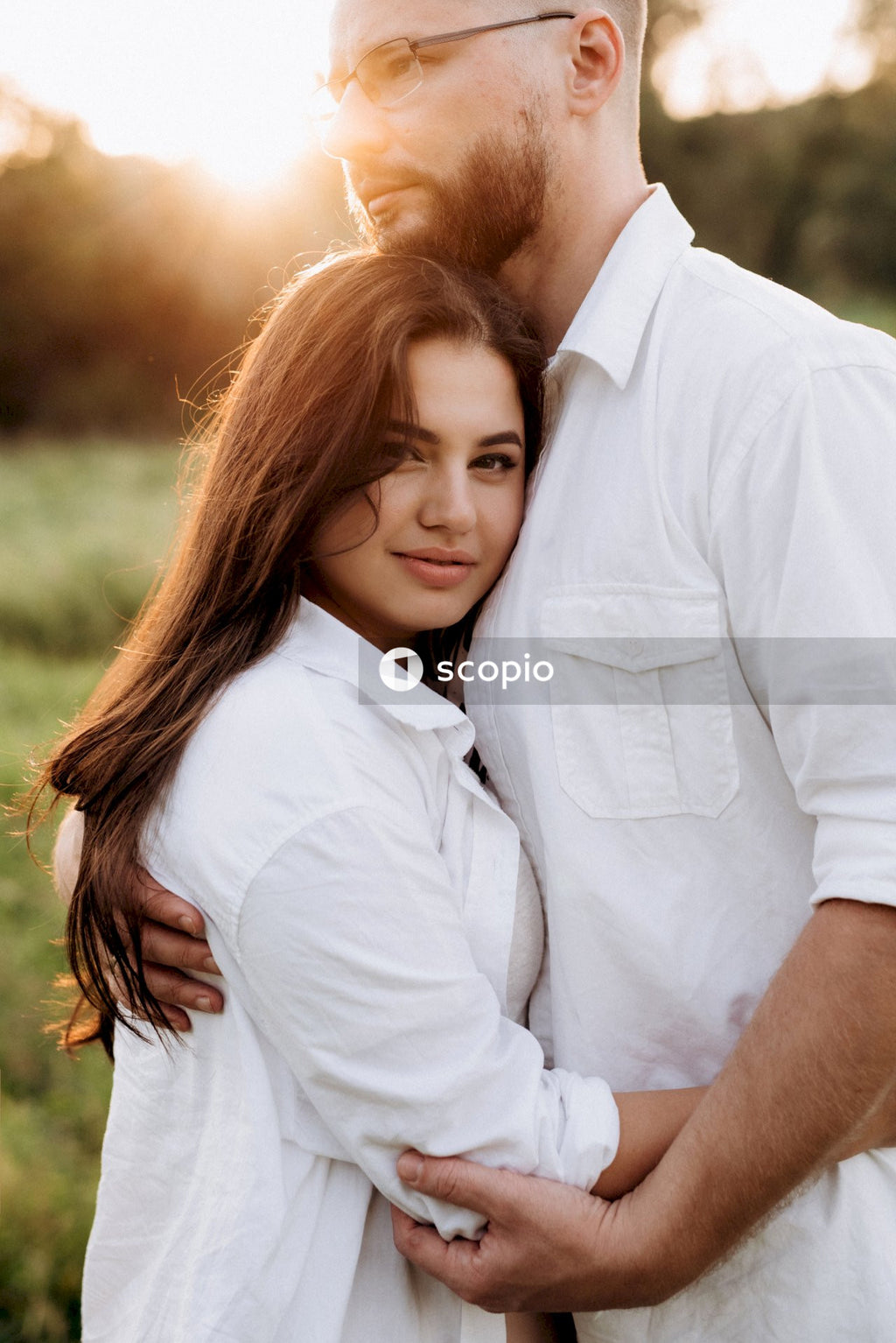 Man in white dress shirt hugging woman in white dress