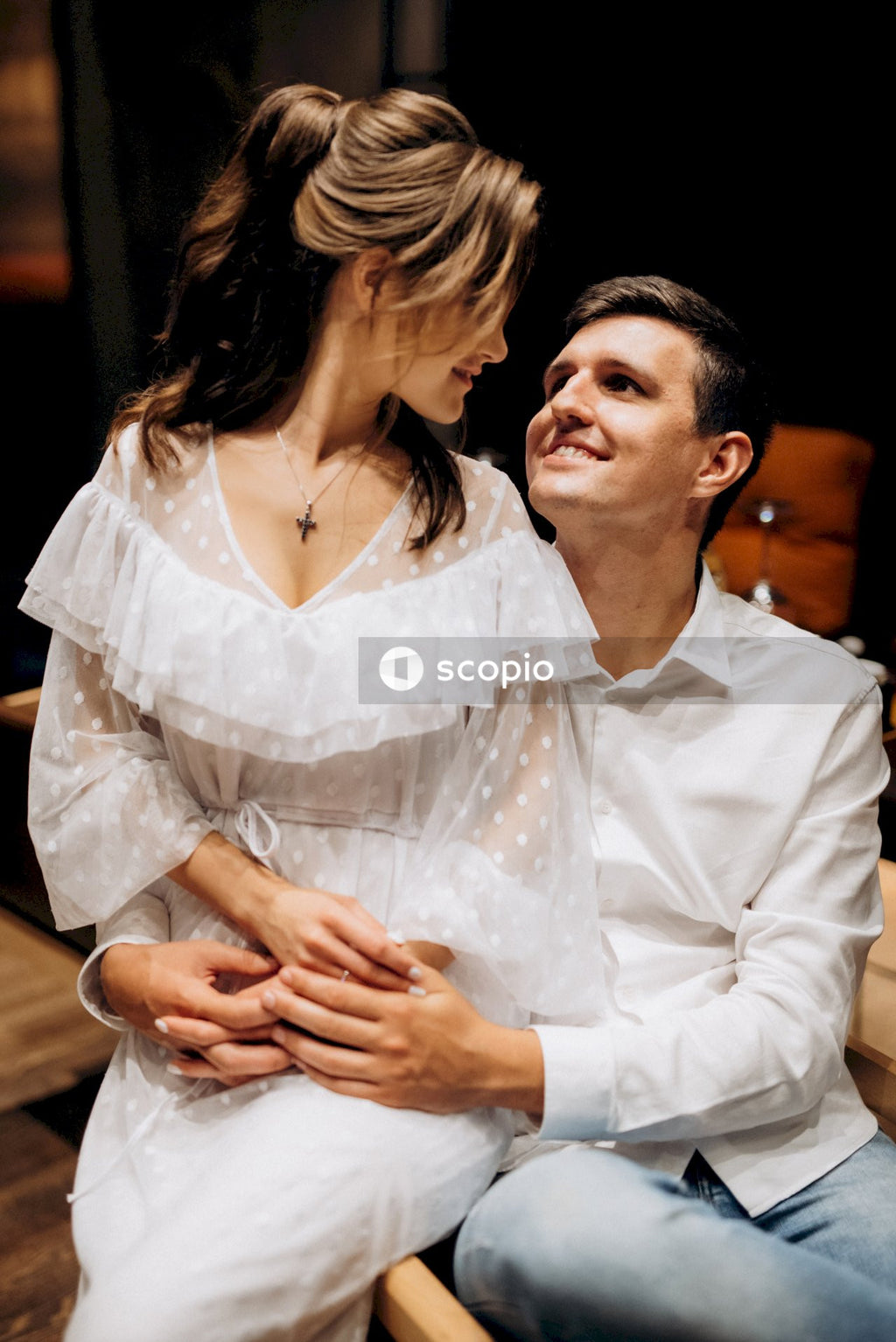 Man in white dress shirt hugging woman in white dress