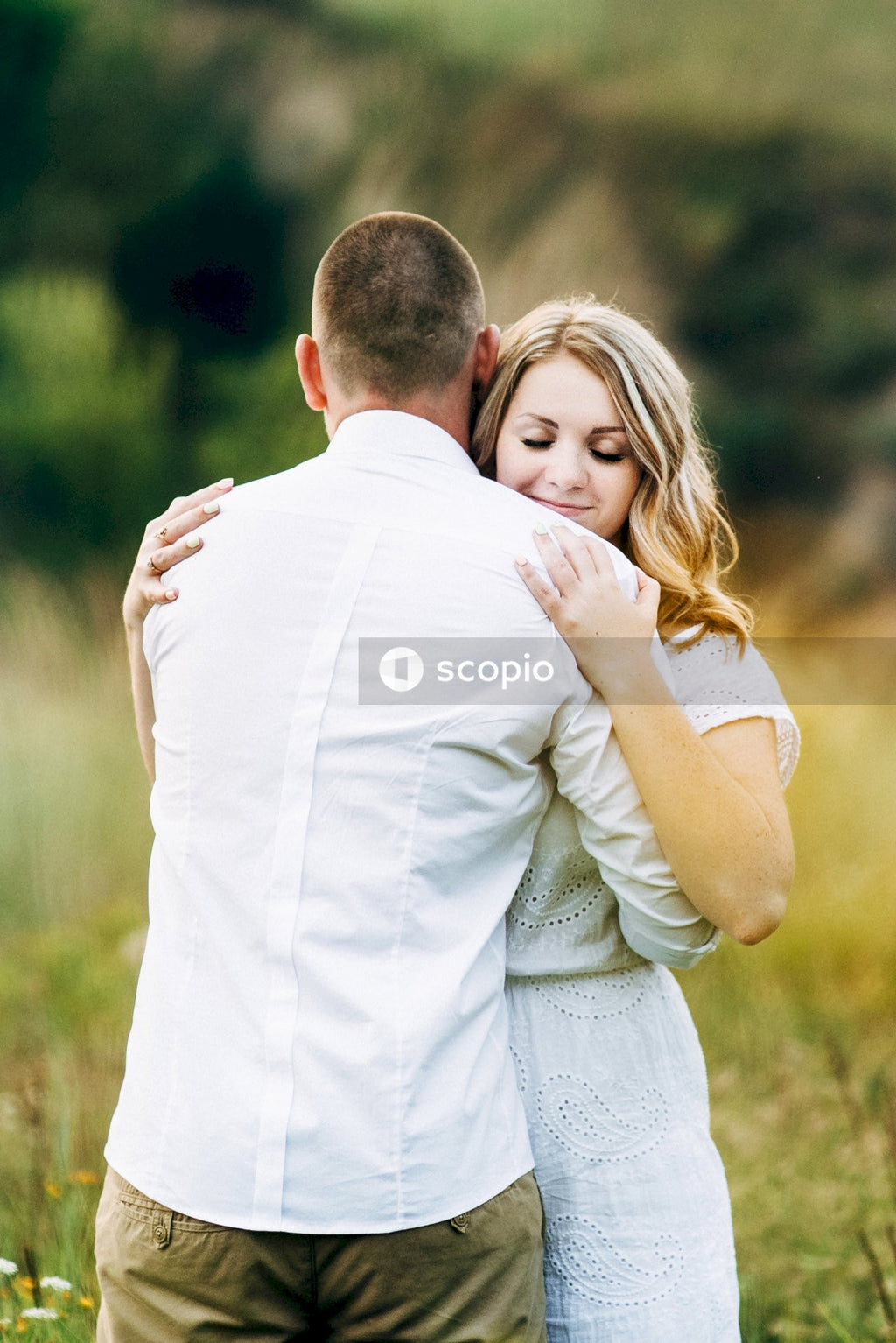 Man in white dress shirt hugging woman in white dress