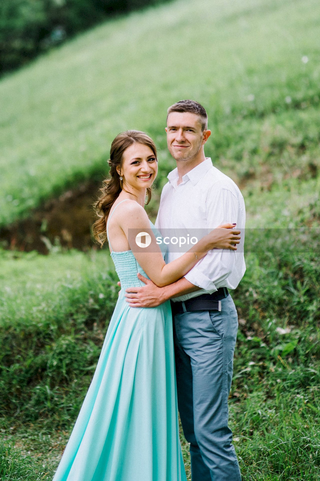 Man in white dress shirt hugging woman in white sleeveless dress