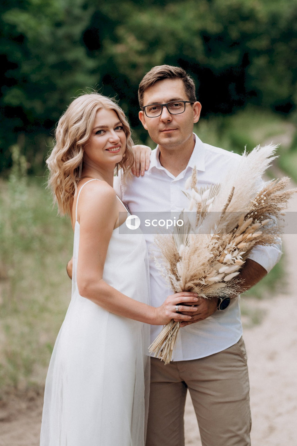 Man in white dress shirt hugging woman in white sleeveless dress
