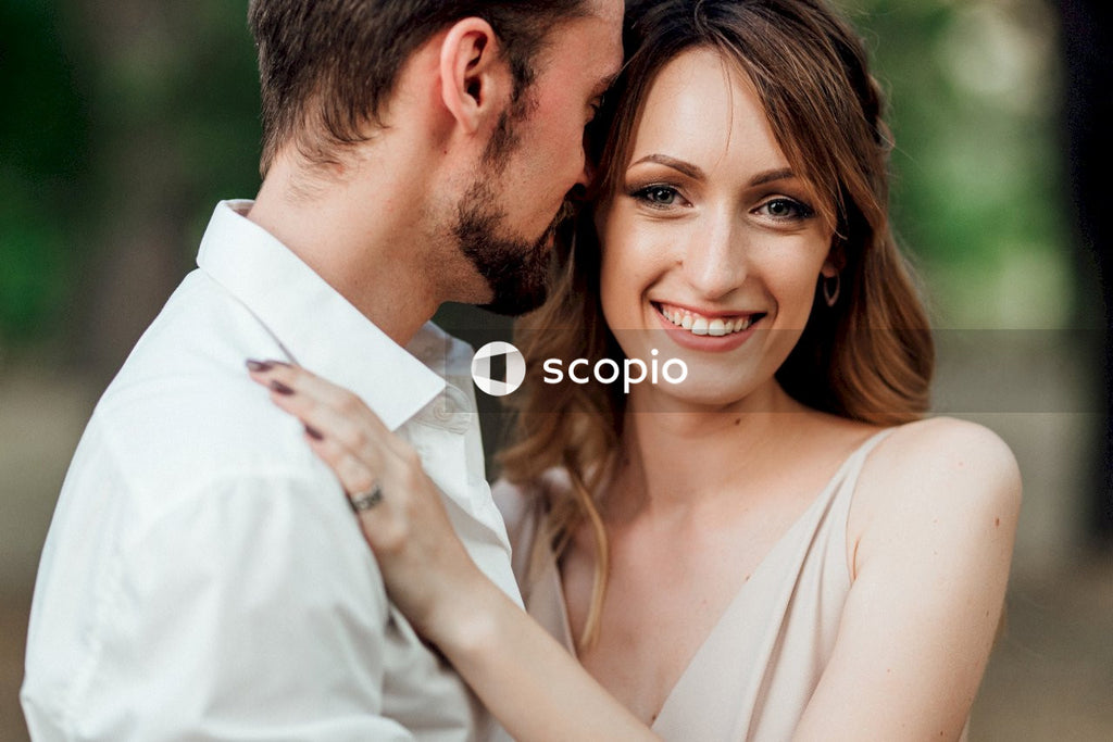 Man in white dress shirt hugging woman in white sleeveless dress