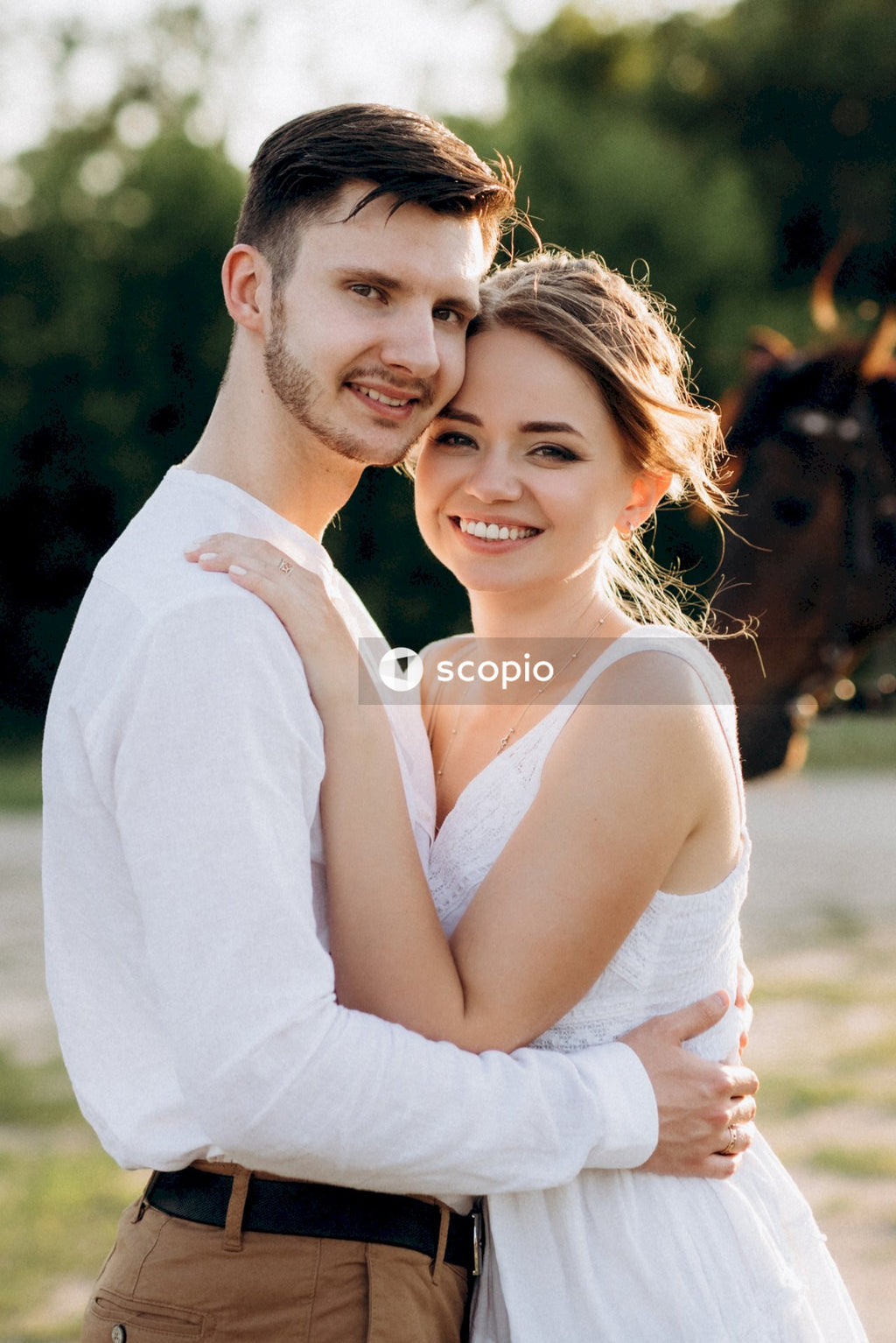 Man in white dress shirt hugging woman in white sleeveless dress
