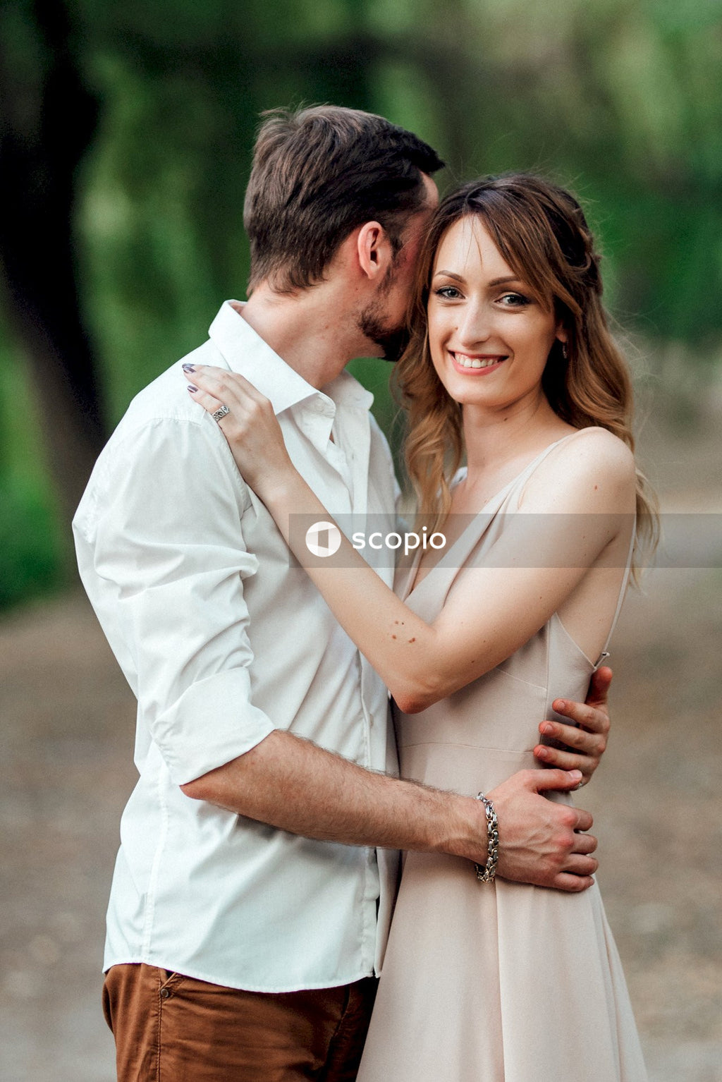 Man in white dress shirt hugging woman in white sleeveless dress