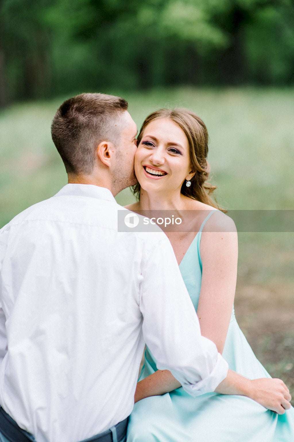 Man in white dress shirt kissing woman in white sleeveless dress