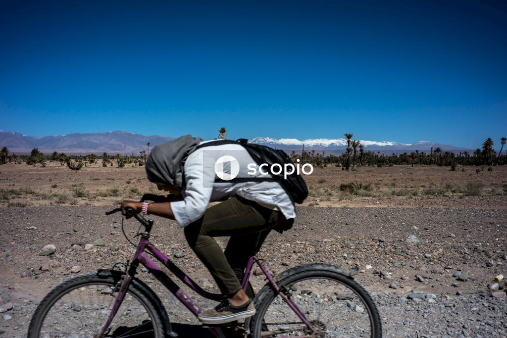 Man in white shirt and blue denim jeans riding black mountain bike on brown field