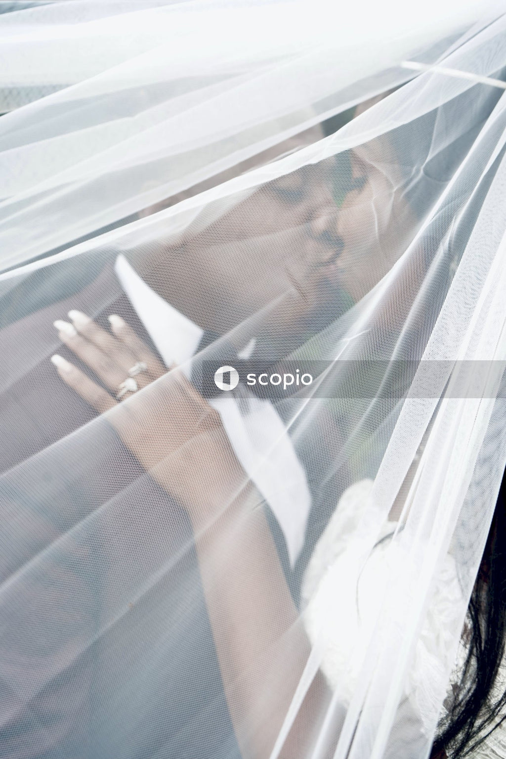 Bride and groom kissing behind light transparent curtain