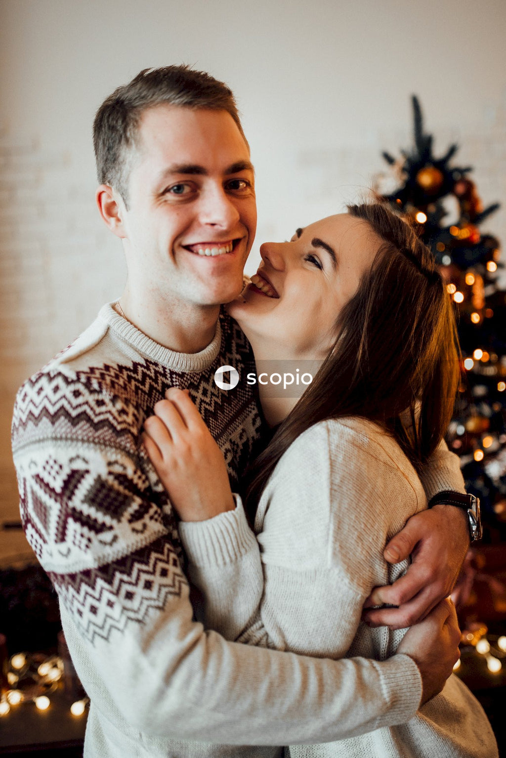 Man in white sweater hugging woman in white sweater