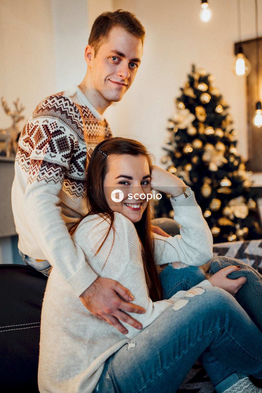 Man in white sweater hugging woman in white sweater
