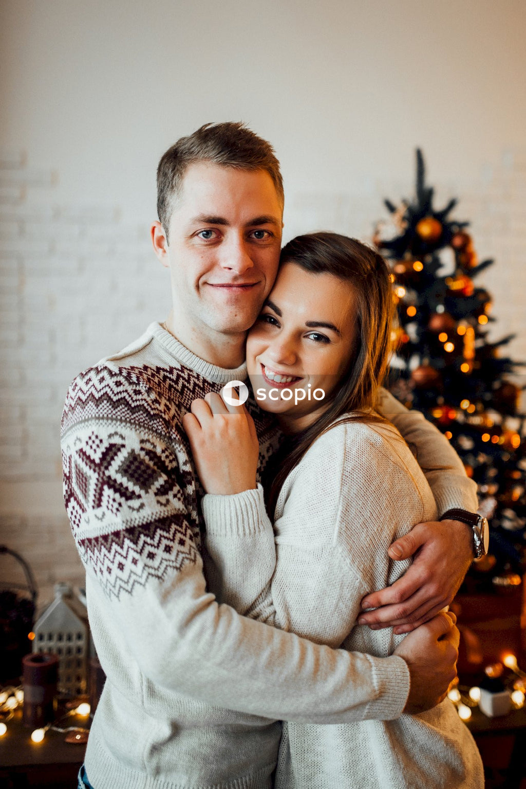 Man in white sweater hugging woman in white sweater
