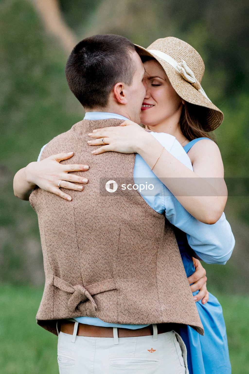 Man in white t-shirt hugging woman in brown sleeveless dress