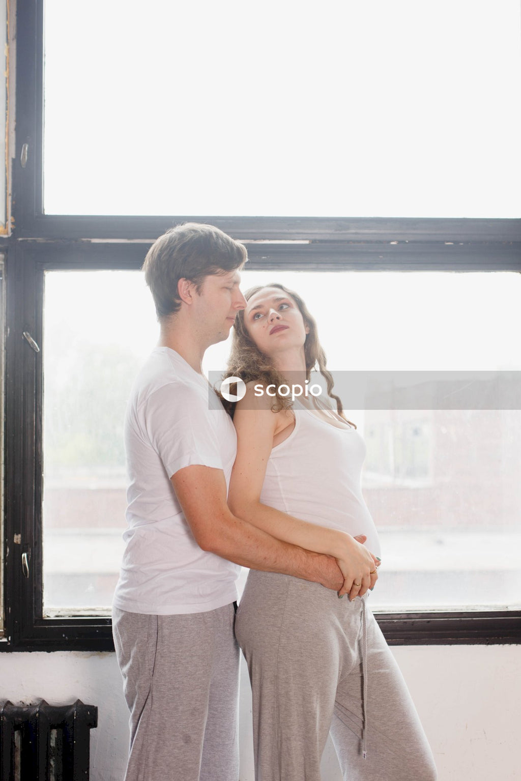 Man in white t-shirt hugging woman in white t-shirt