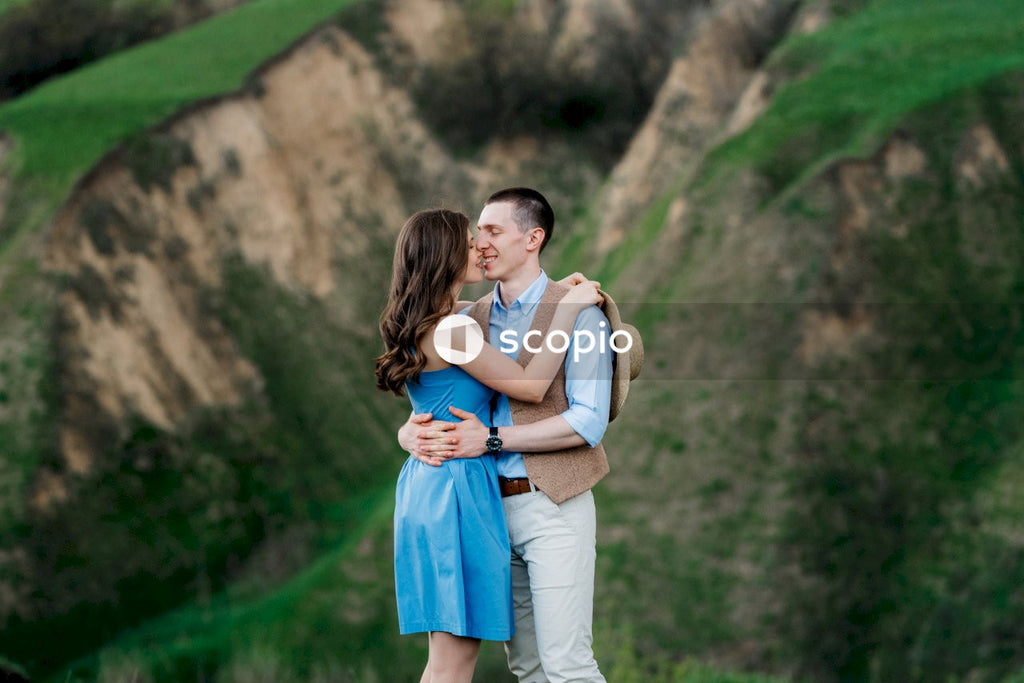 Man in white tank top hugging woman in blue sleeveless dress
