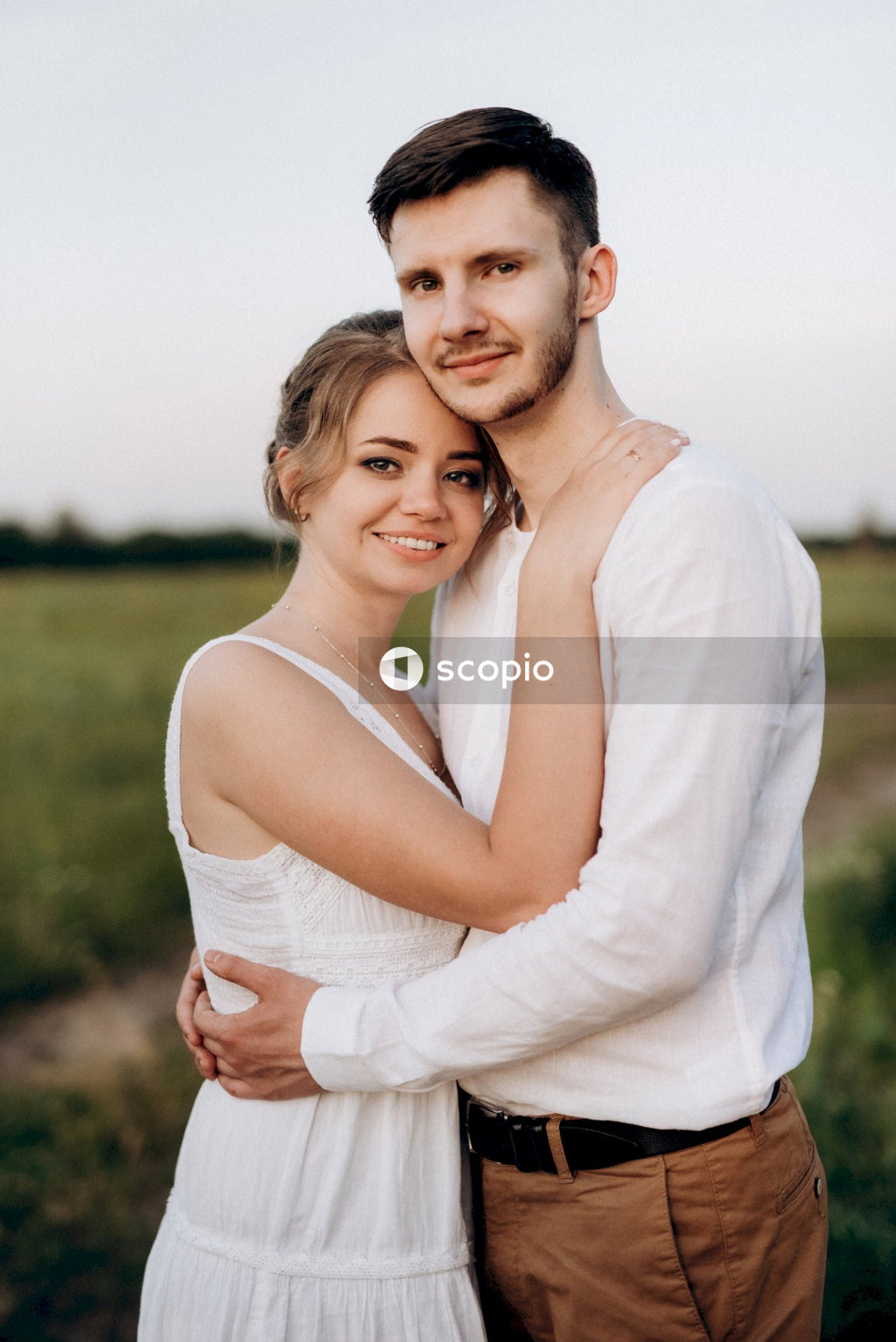 Man in white tank top hugging woman in white sleeveless dress