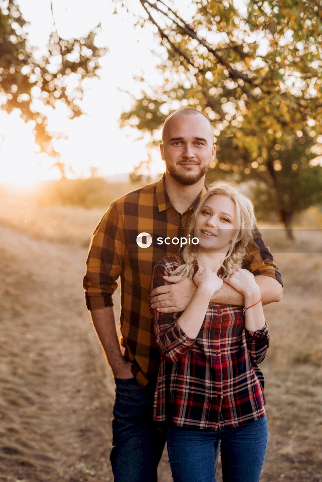 Man in yellow and black plaid dress shirt hugging woman in white and black stripe dress
