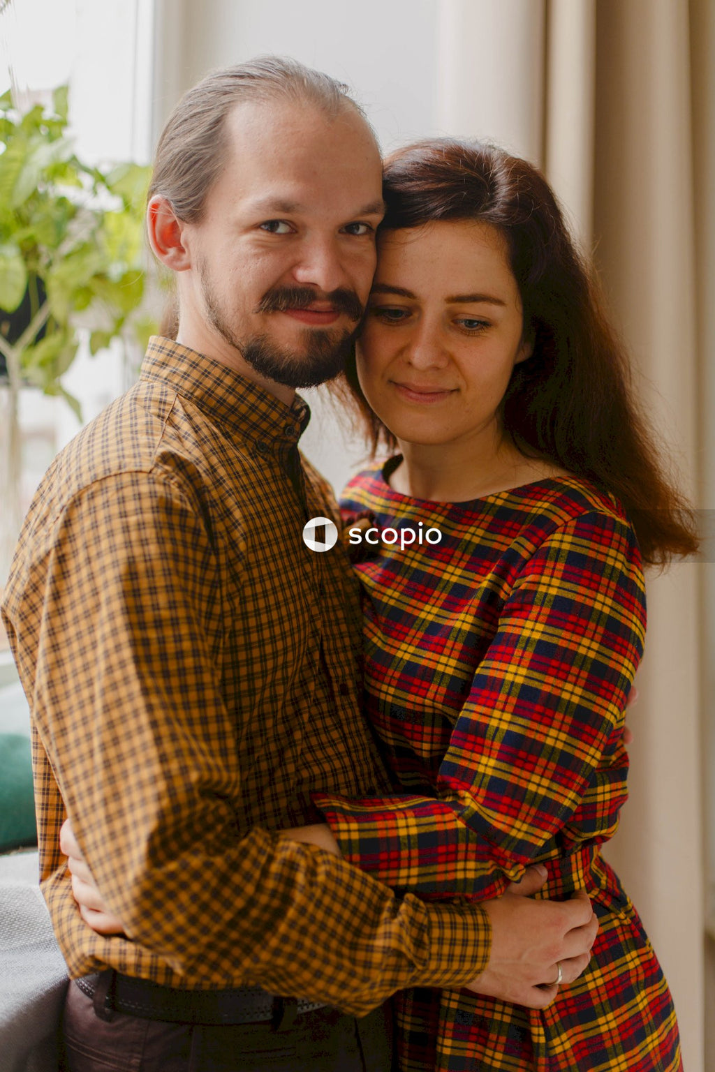 Man in yellow and black plaid dress shirt hugging woman in yellow and black plaid dress