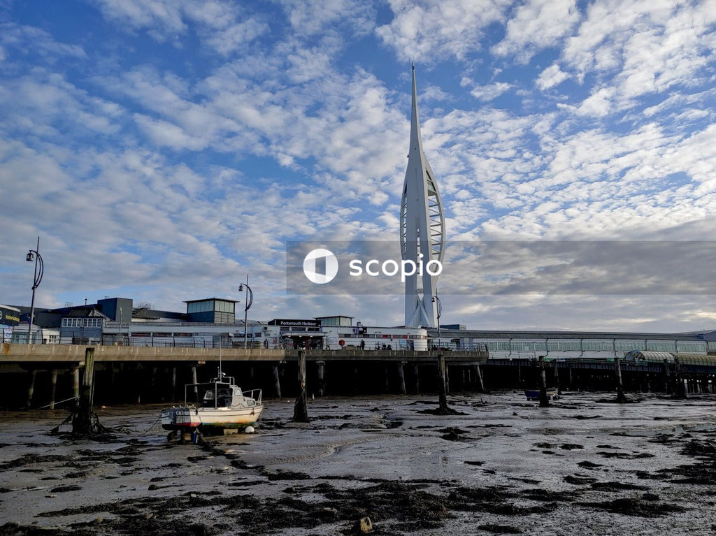 Old Unused white boat on beach during low tide under blue sky and white clouds