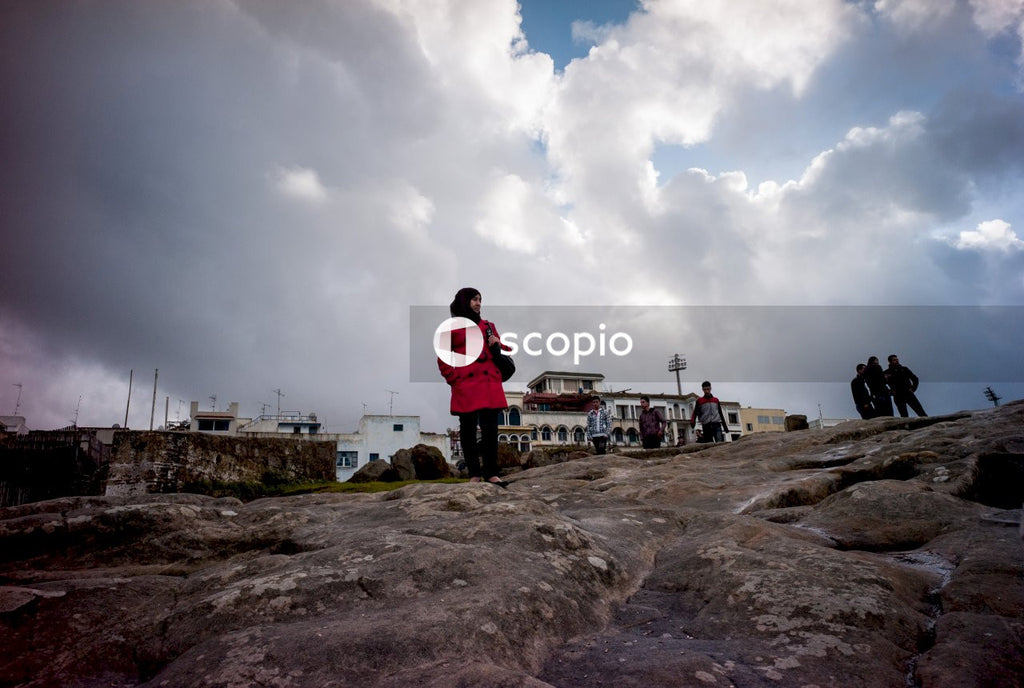 People standing on brown rock under white clouds