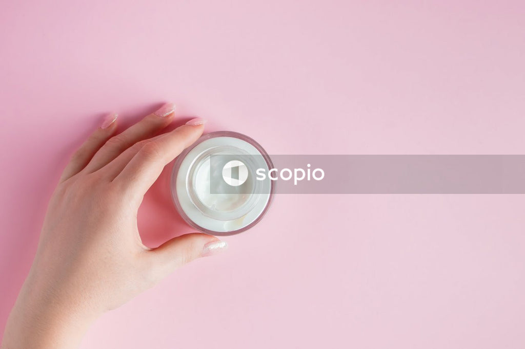 Person holding round white plastic container