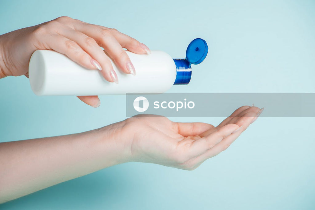 Person holding white and blue plastic bottle
