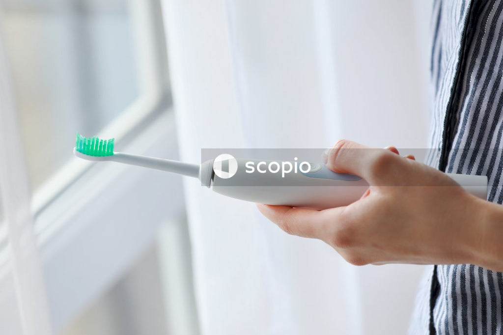 Person holding white and green toothbrush
