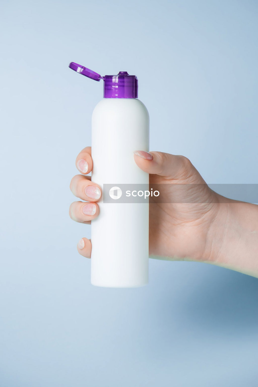 Person holding white and purple plastic bottle