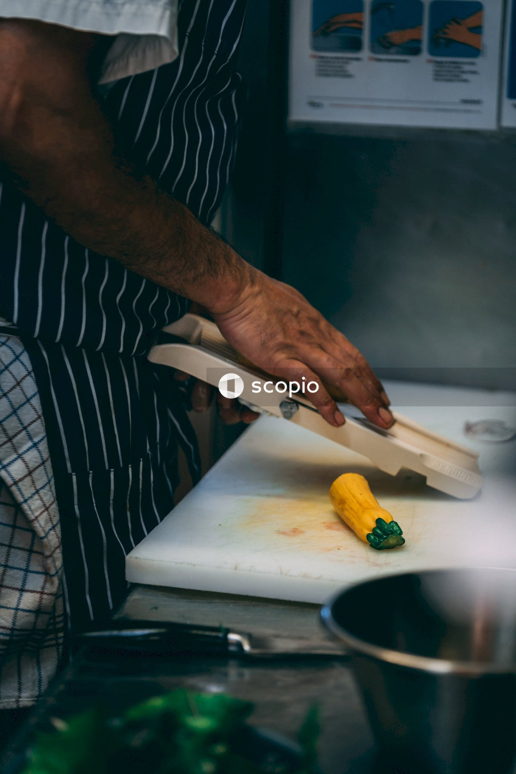 Person in black and white stripe shirt holding white chopping board