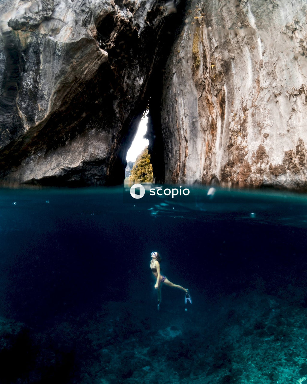 Person in blue water near brown rock formation