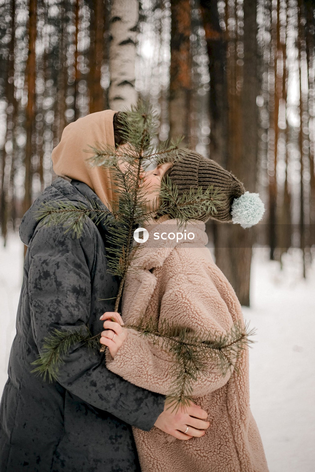 Young couple kissing each other in snow covered woods