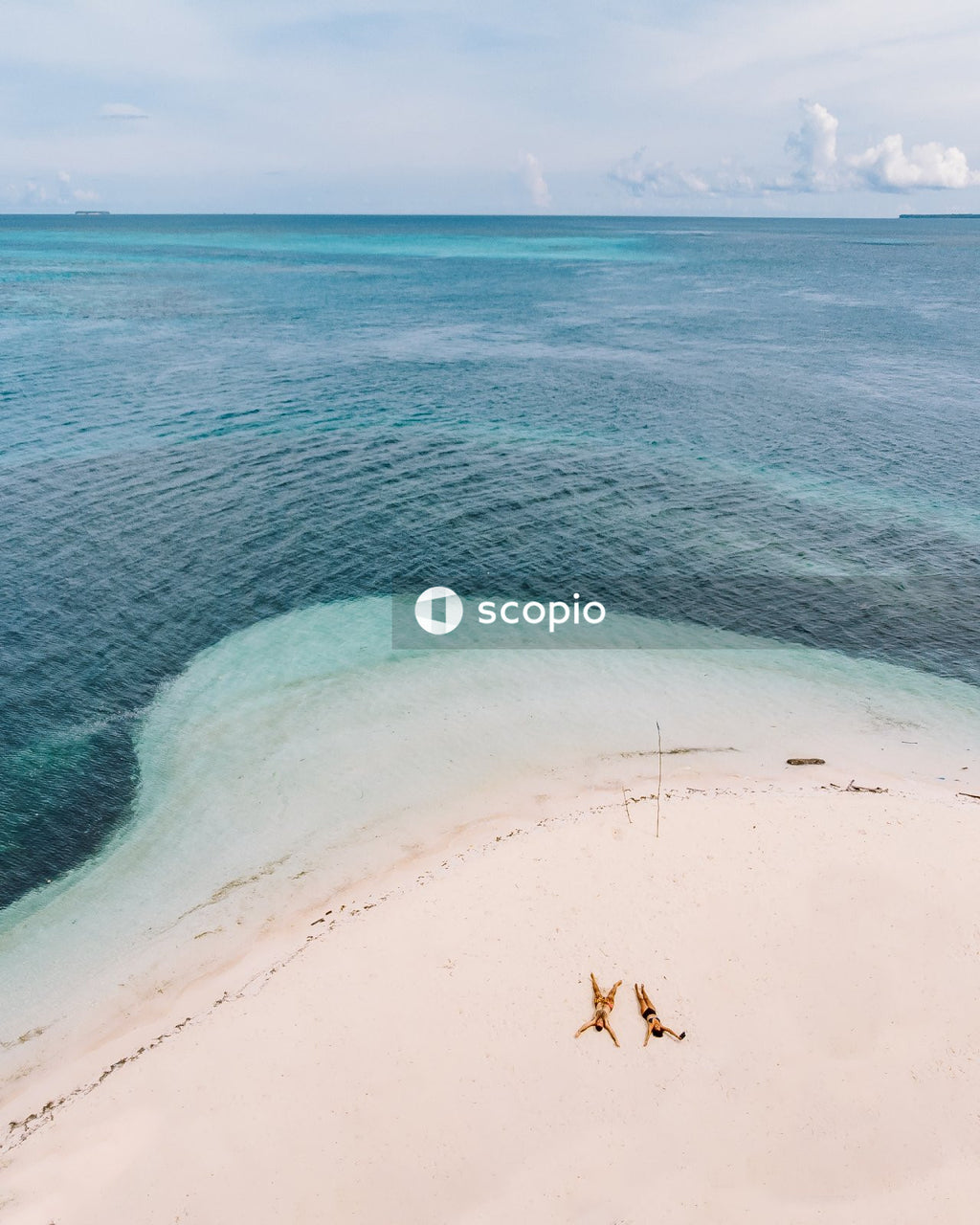 Man and a woman in bathing suits laying on the beach
