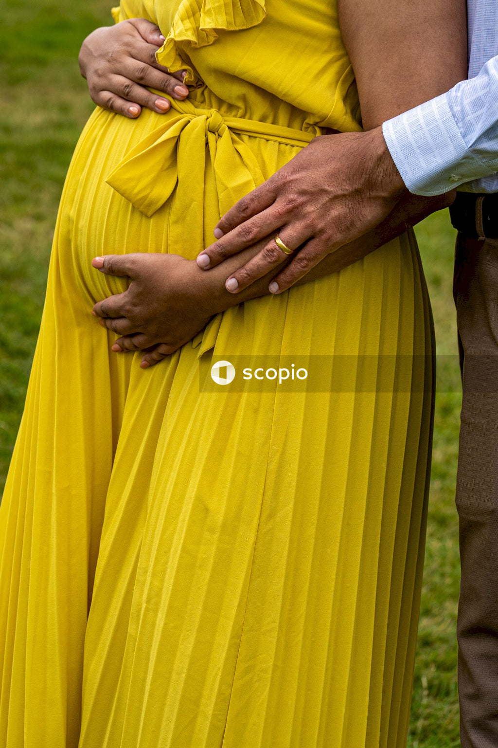 Cropped image of pregnant woman in yellow dress and a man standing outdoor
