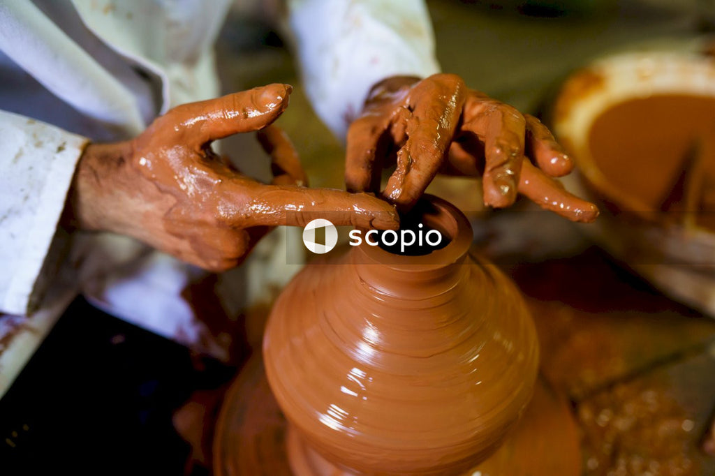Person making clay pot with brown clay