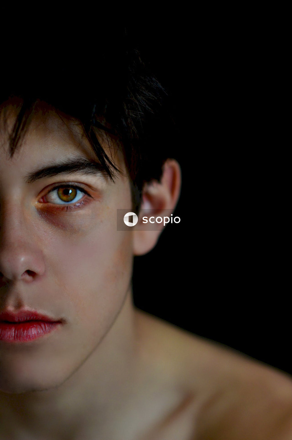 Portrait of topless young man against dark background