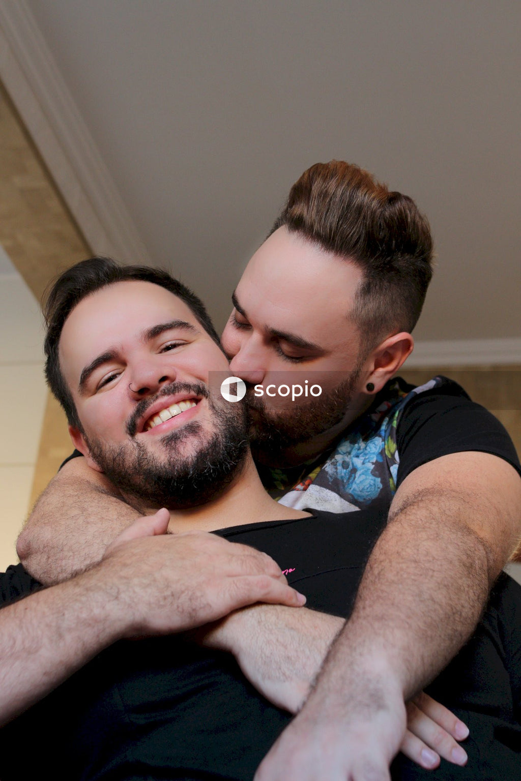 Queer man kissing his partner indoor