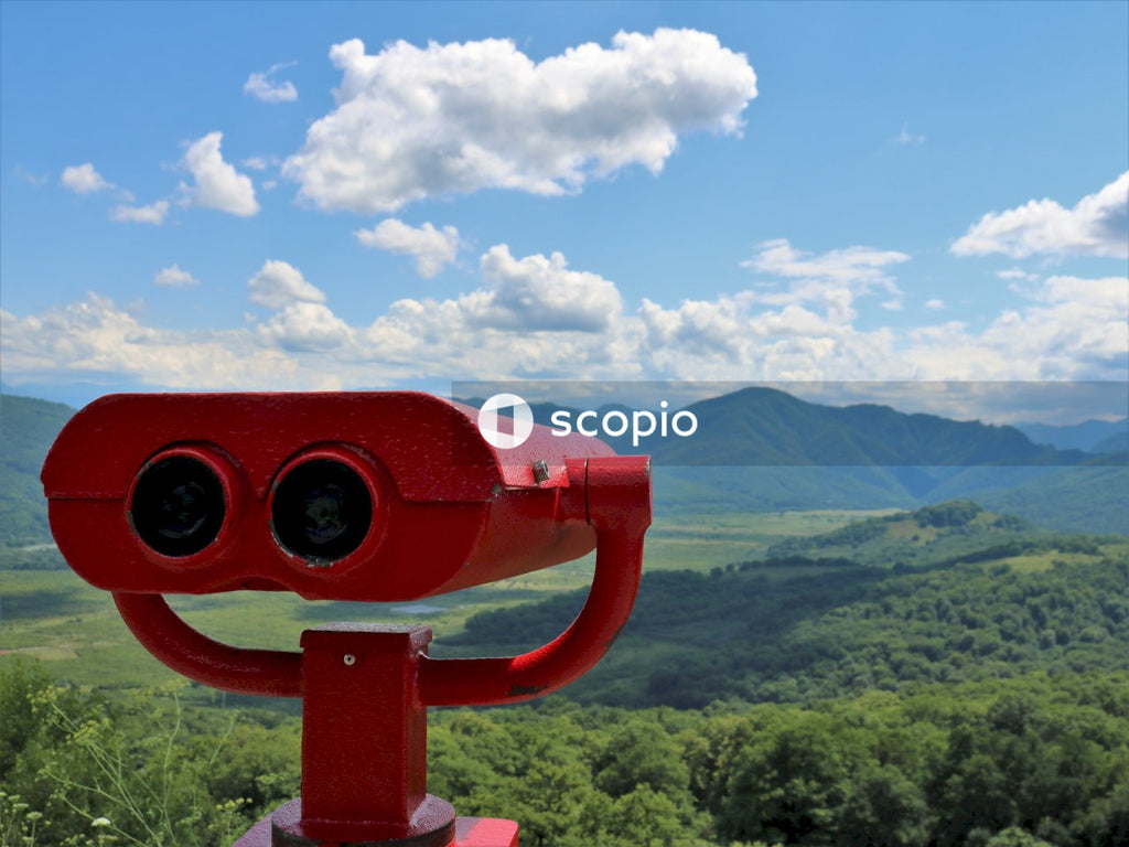 Red and black binoculars on top of green mountain