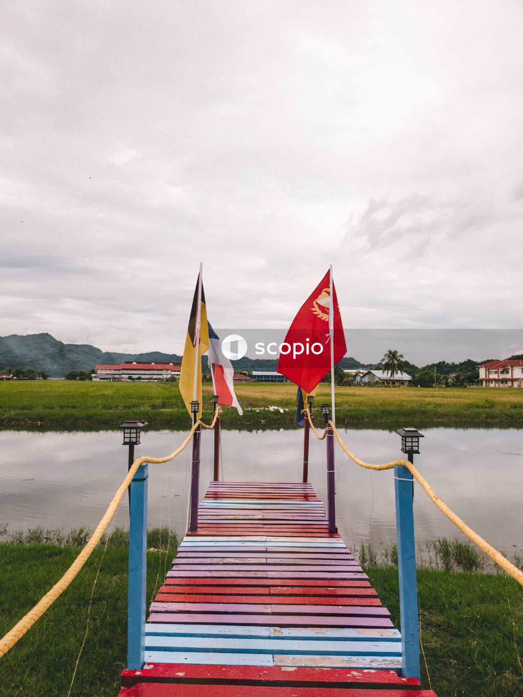 Red and white flag on brown wooden bridge over river