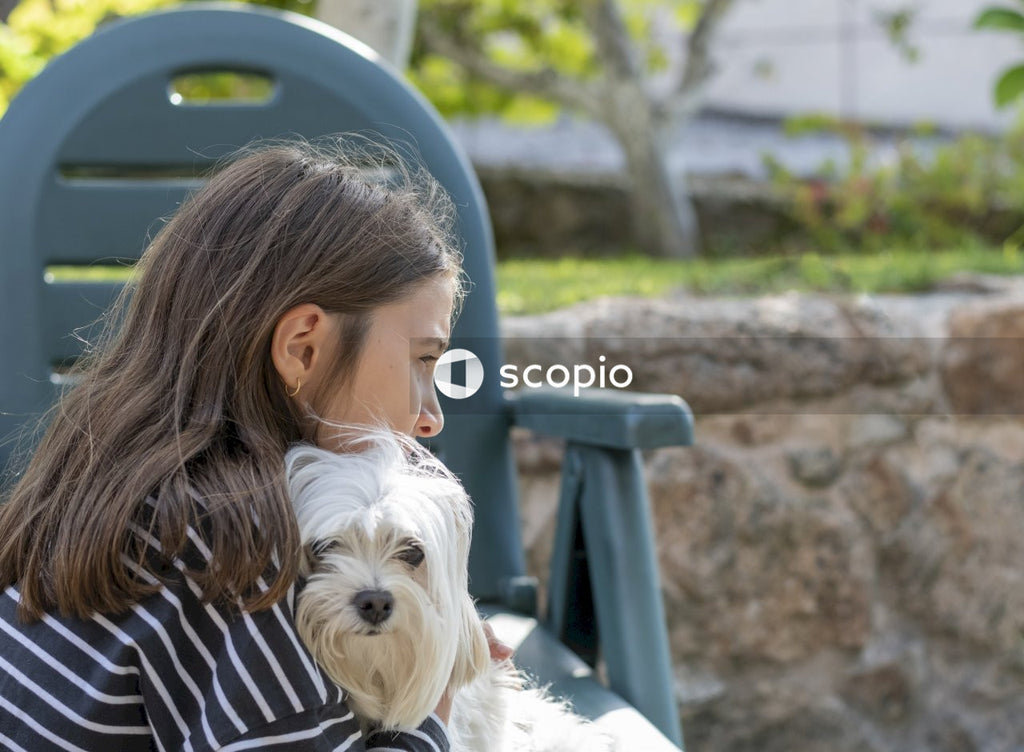 Side view of a girl hugging a Bichon Maltese dog.