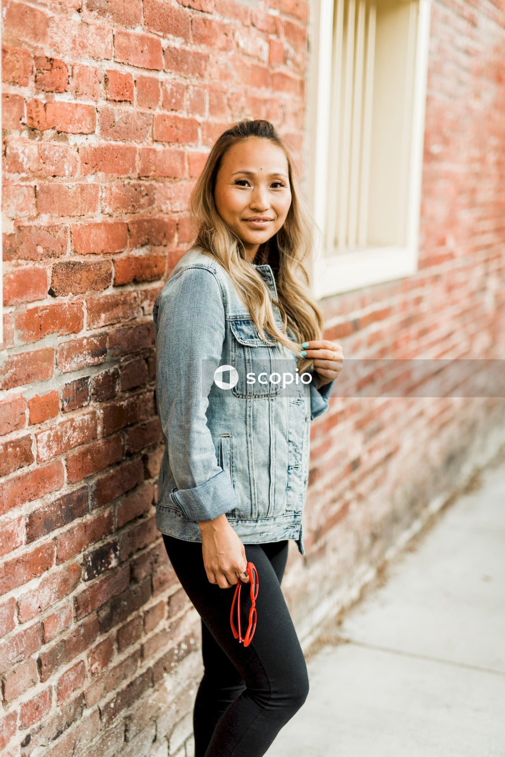 Side view of woman in denim jacket leaning on a wall