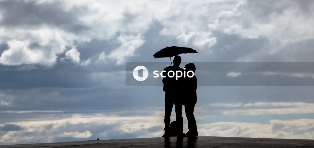 Silhouette of couple holding umbrella under cloudy sky