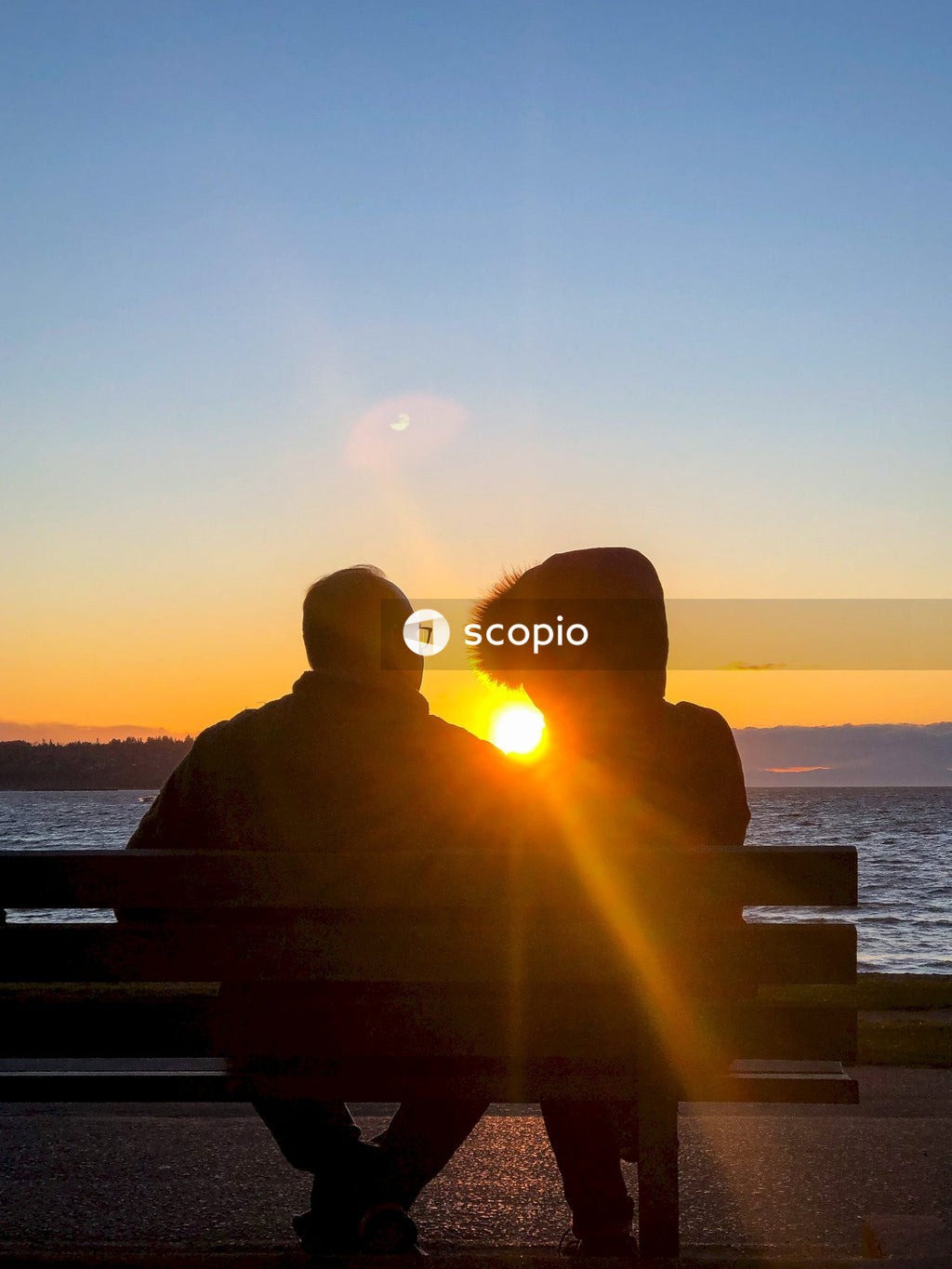 Silhouette of couple sitting on bench during sunset