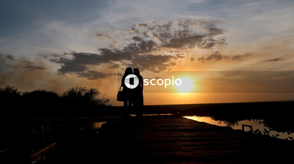 Silhouette of couple standing on wooden dock during sunset