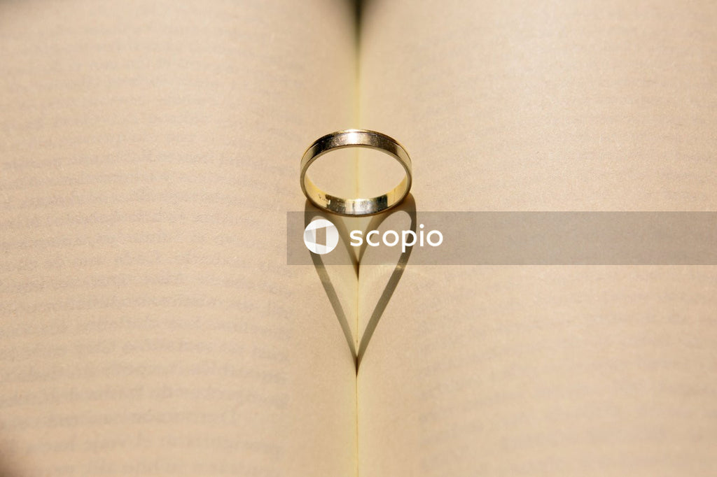 Silver wedding band casting a heart shaped shadow inside a book