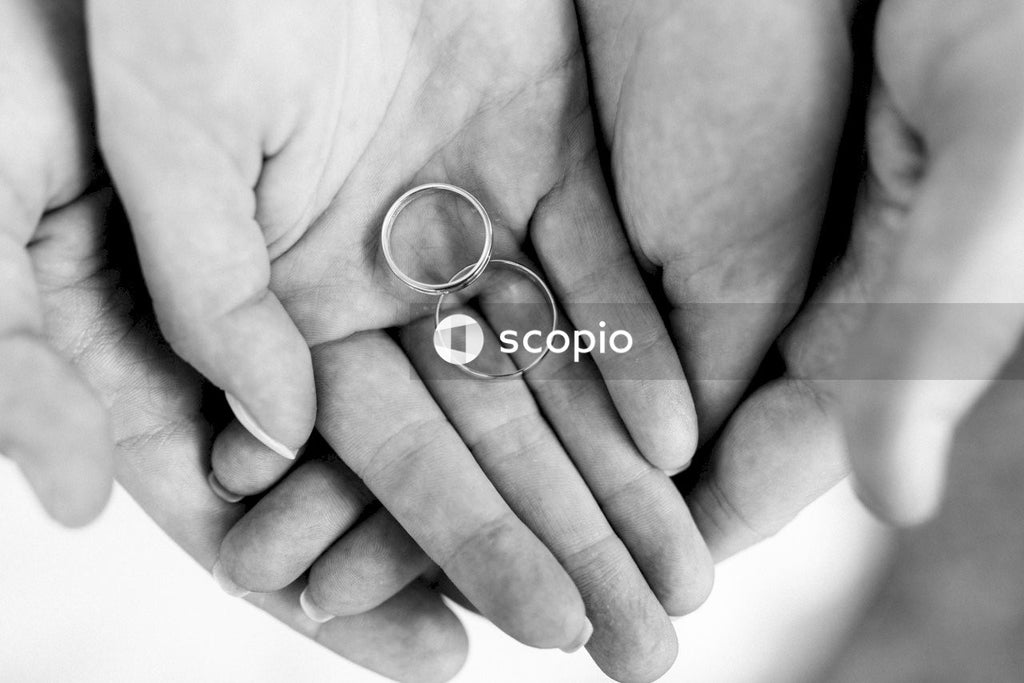Cropped image of hands holding two wedding rings in grayscale
